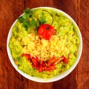 Tex Mex guacamole in bowl on brown wooden background.