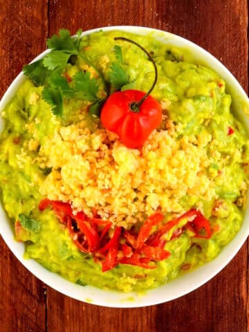 Tex Mex guacamole in bowl on brown wooden background.