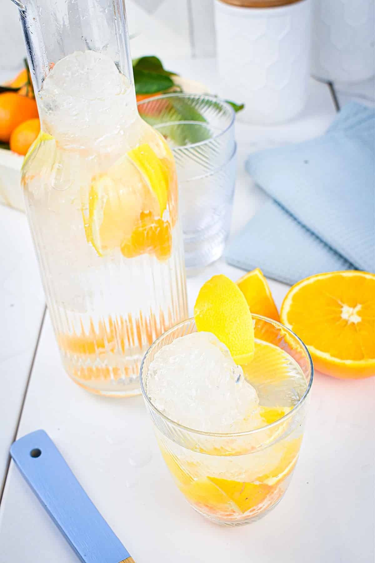 Citrus fruit infused water in glass and pitcher.