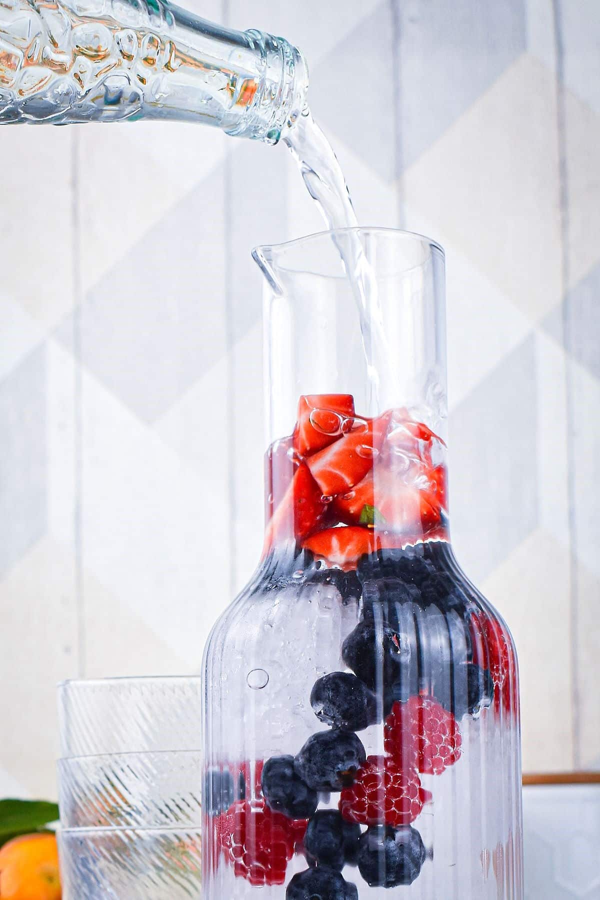Mixed berry infused water in pitcher.