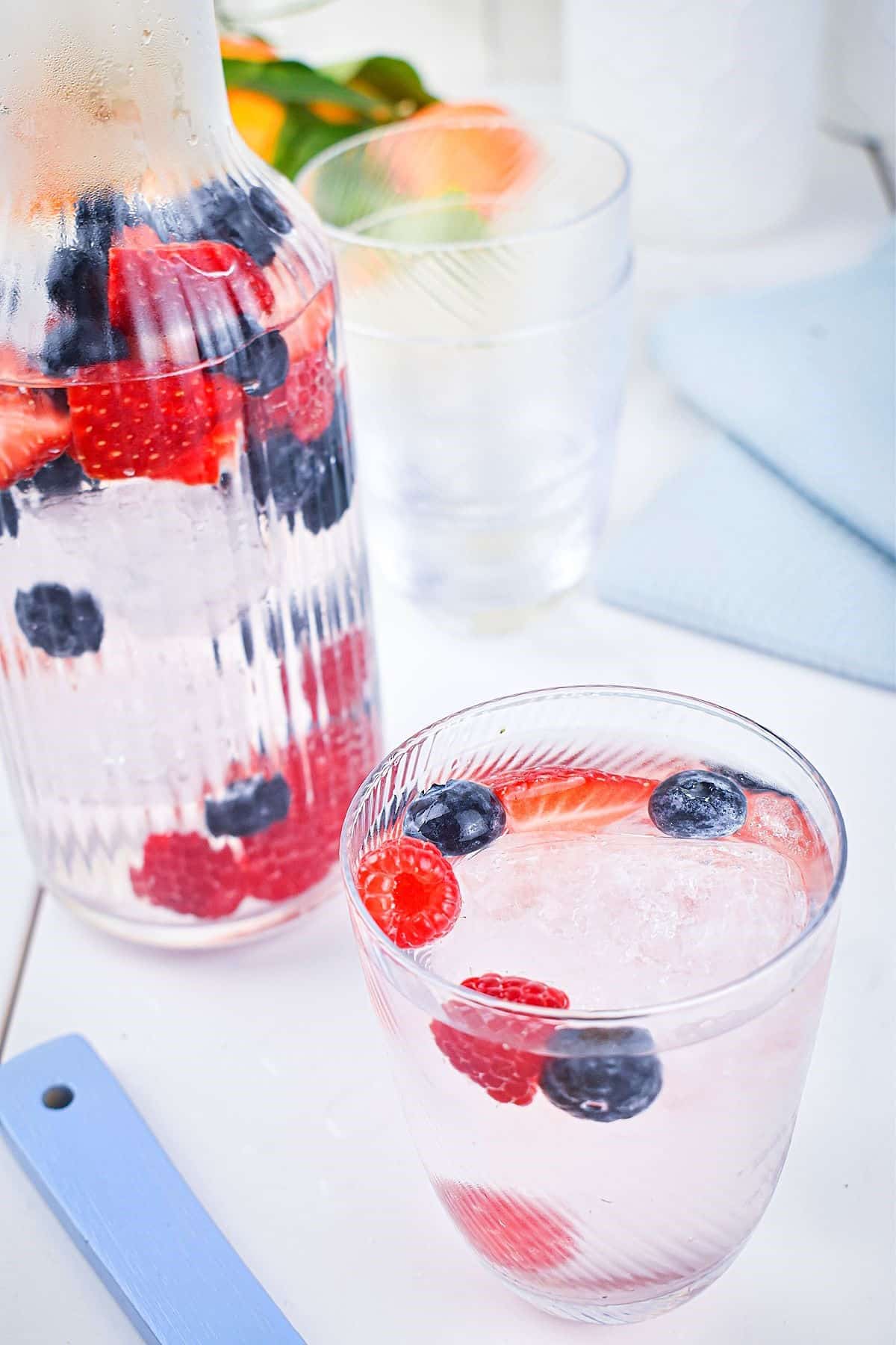 Mixed berry infused water in pitcher and glass.