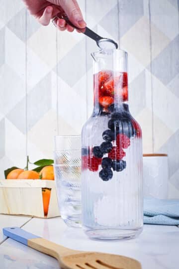 Fruit infused water with sugar in pitcher.