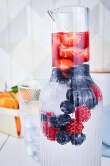 Fruit infused water in glass pitcher.