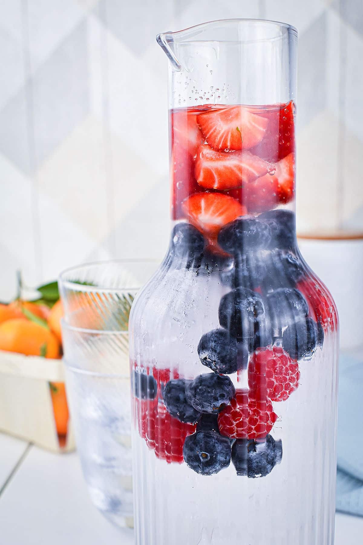Fruit infused water in glass pitcher.