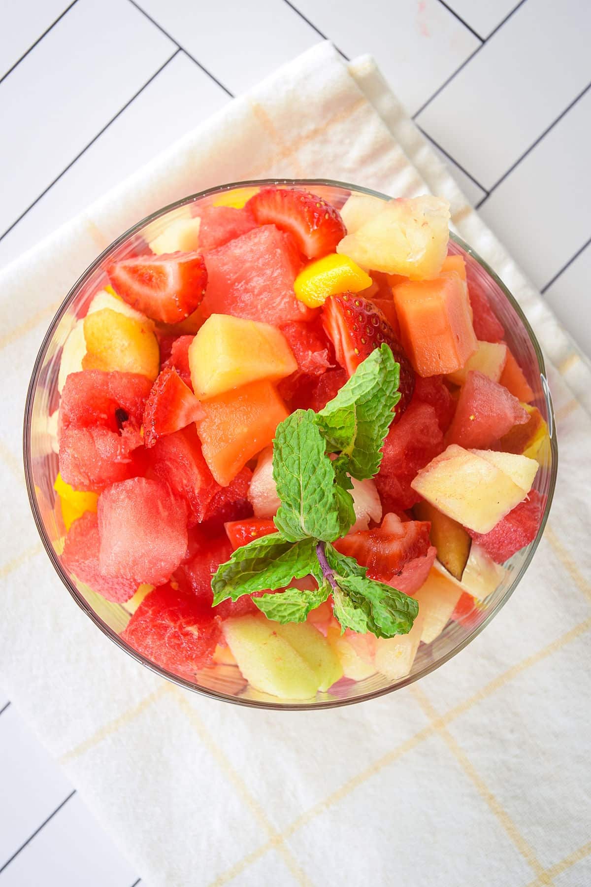 Fruit salad in a glass bowl with fresh mint.