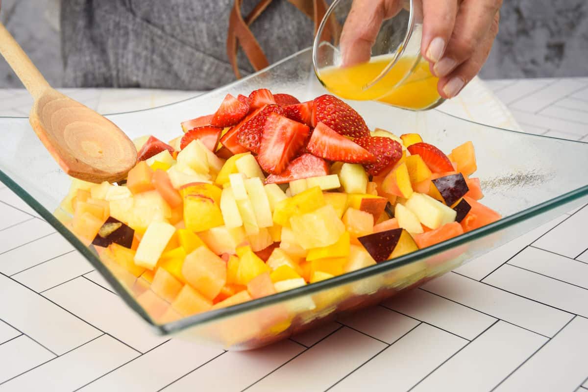Orange juice pouring over chopped fruit.