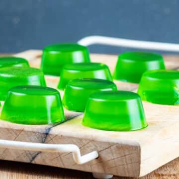 Green homemade gummies on cutting board.