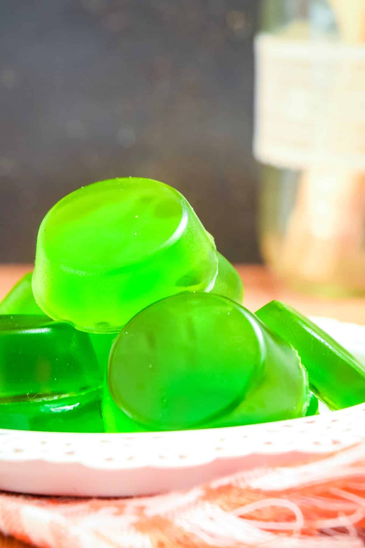 Green homemade gummies stacked on plate.
