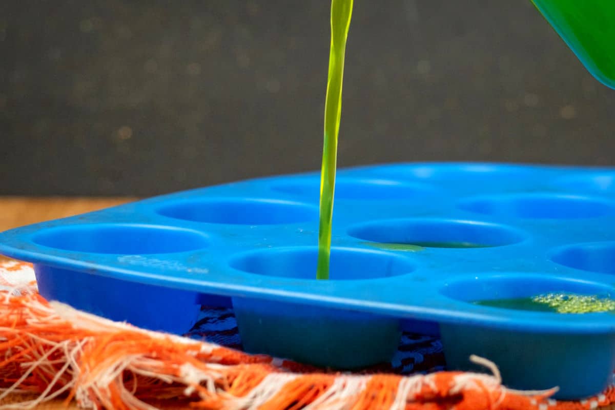 Homemade gummy mixture pouring into blue candy mold.