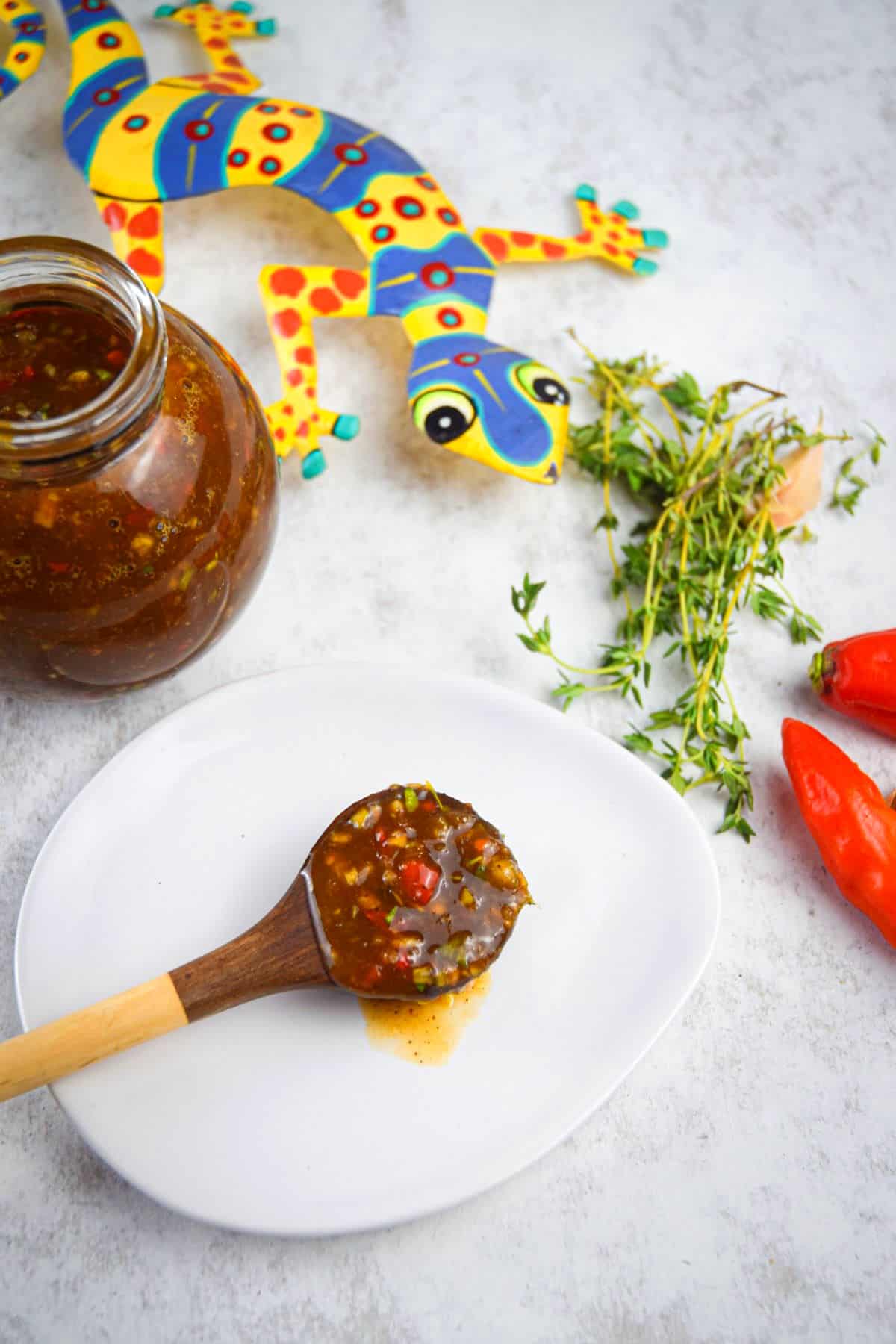 Jerk sauce on spoon on white plate.