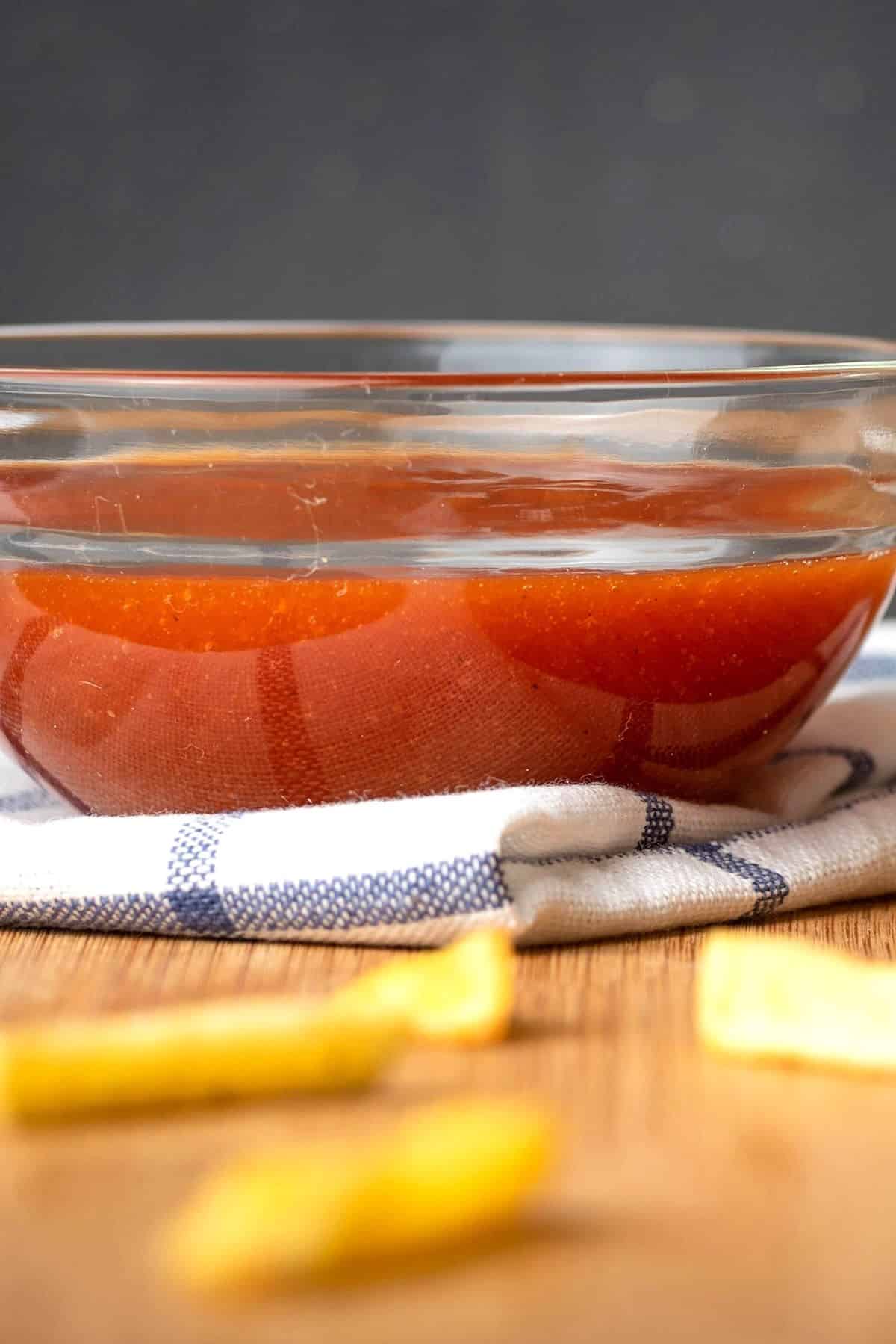 Homemade ketchup in a bowl on kitchen towel.