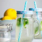 Lemonade in jars with basil and blue straws.