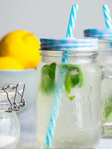Lemonade in jars with basil and blue straws.