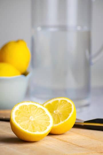 Lemon sliced in half on cutting board.