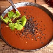 Mole sauce in a bowl with cilantro and black sesame seeds.