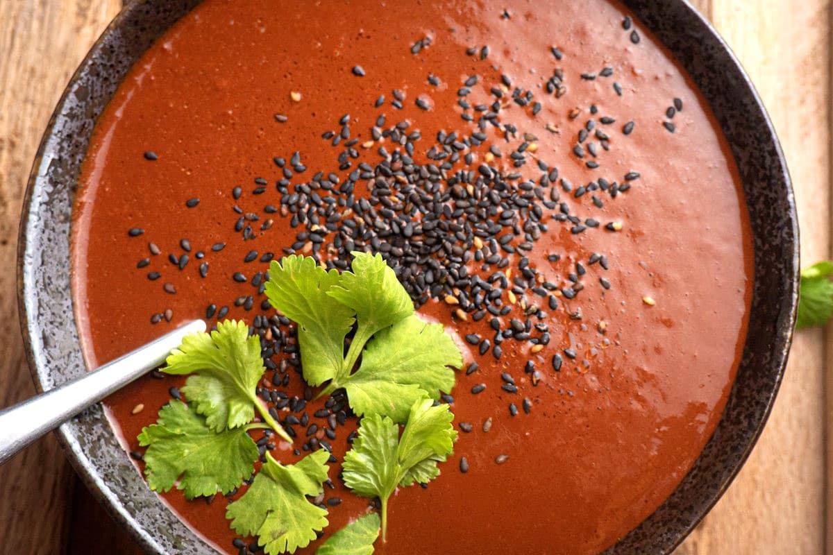 Mole sauce in a bowl with cilantro and black sesame seeds.