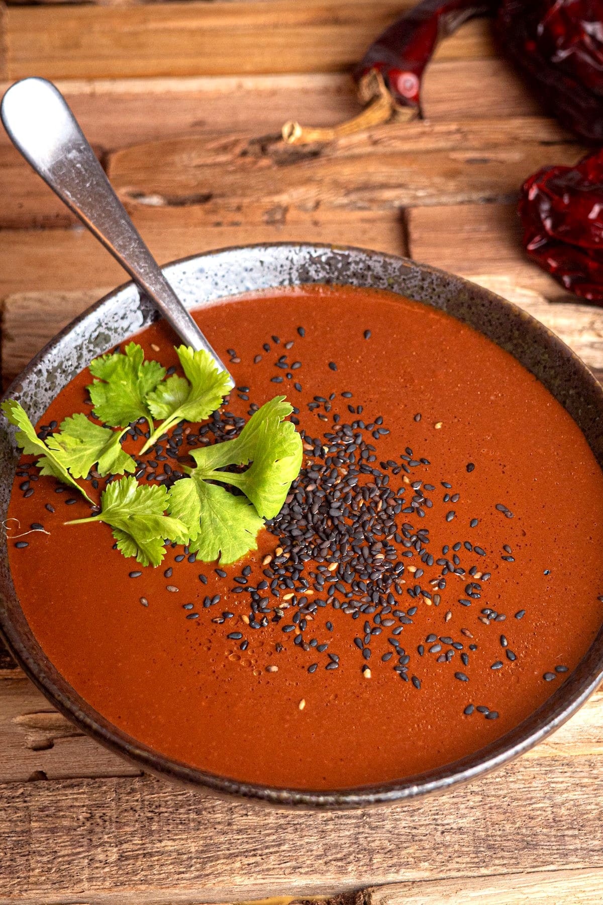 Mole sauce in a bowl with cilantro and black sesame seeds.