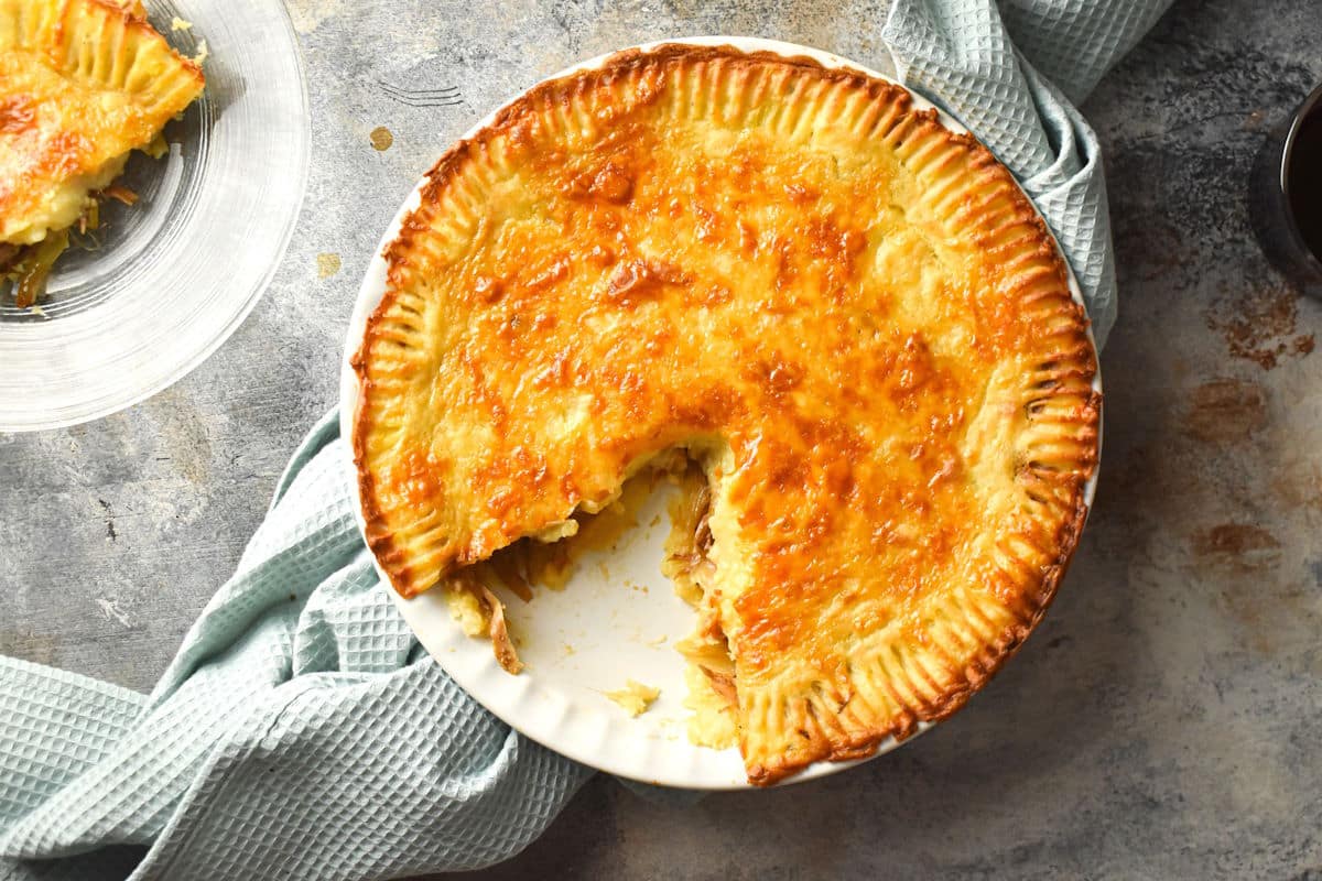 Shepherd's pie in white pie dish with a slice pulled out.