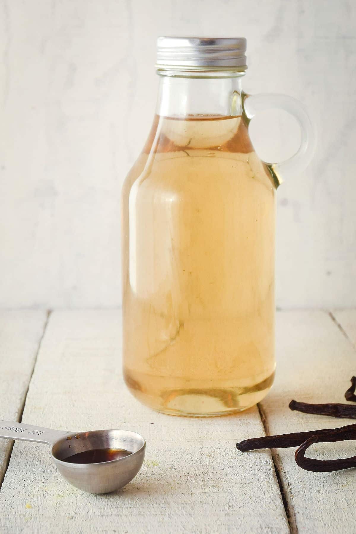 How to Make Simple Syrup Step 5 - Variation 2 Simple syrup in bottle with vanilla beans on the side.