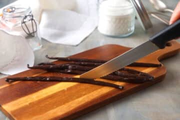 Vanilla beans on cutting board with knife.