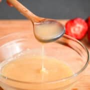 White chocolate ganache drizzling from spoon into bowl.