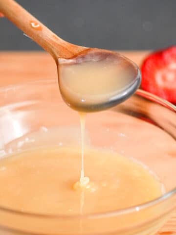 White chocolate ganache drizzling from spoon into bowl.
