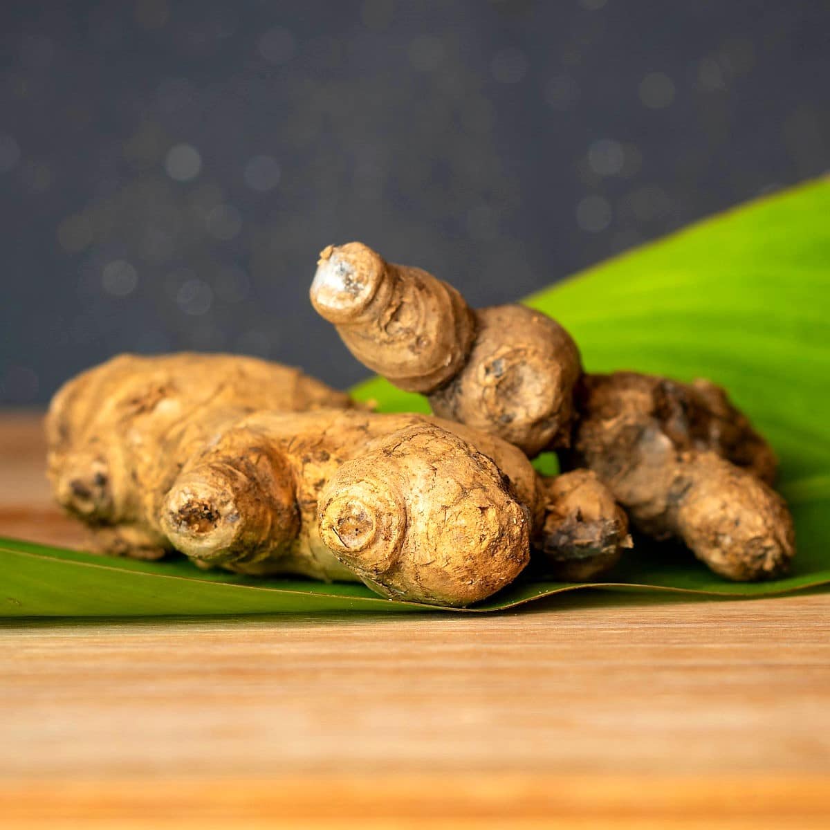Fresh ginger root on large green leaf.