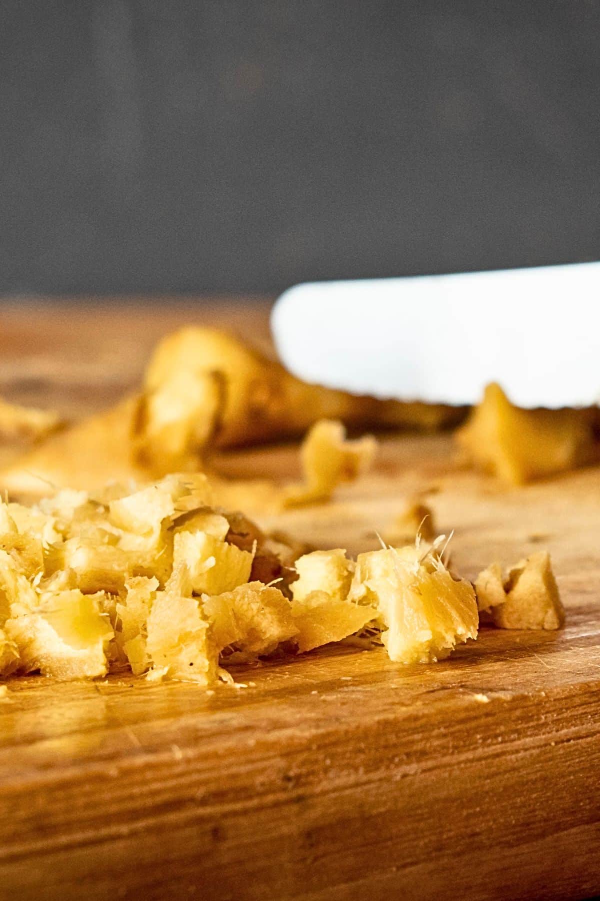 Freshly chopped ginger root on cutting board with knife.