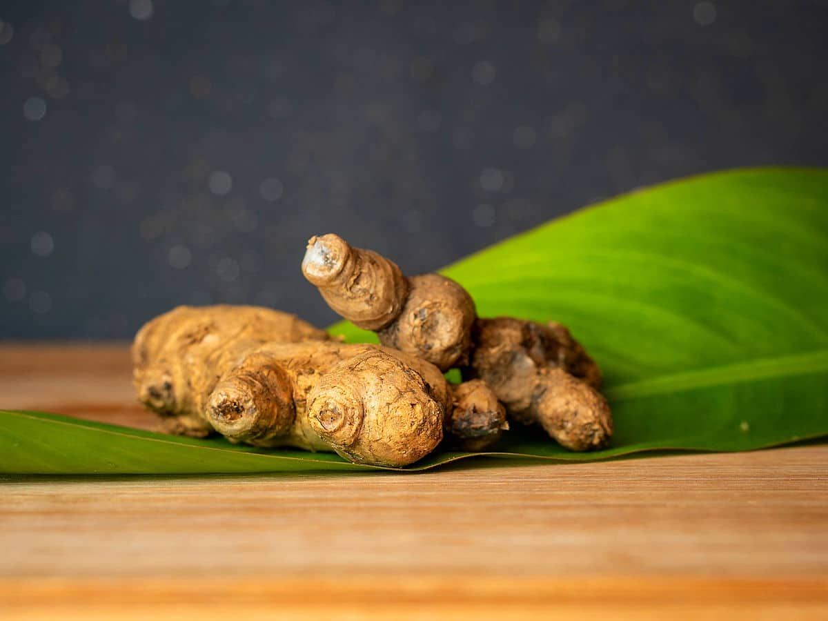 Fresh ginger root on leaf on cutting board.