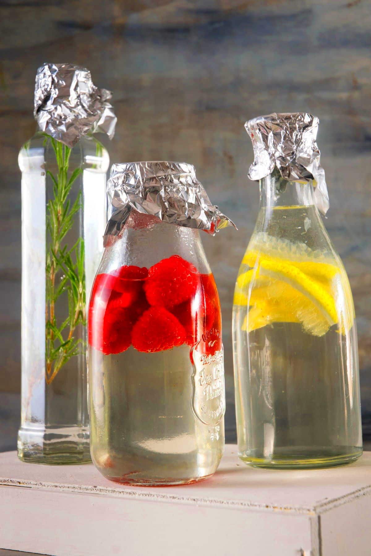 Jars of infused cocktail syrups with foil on top.