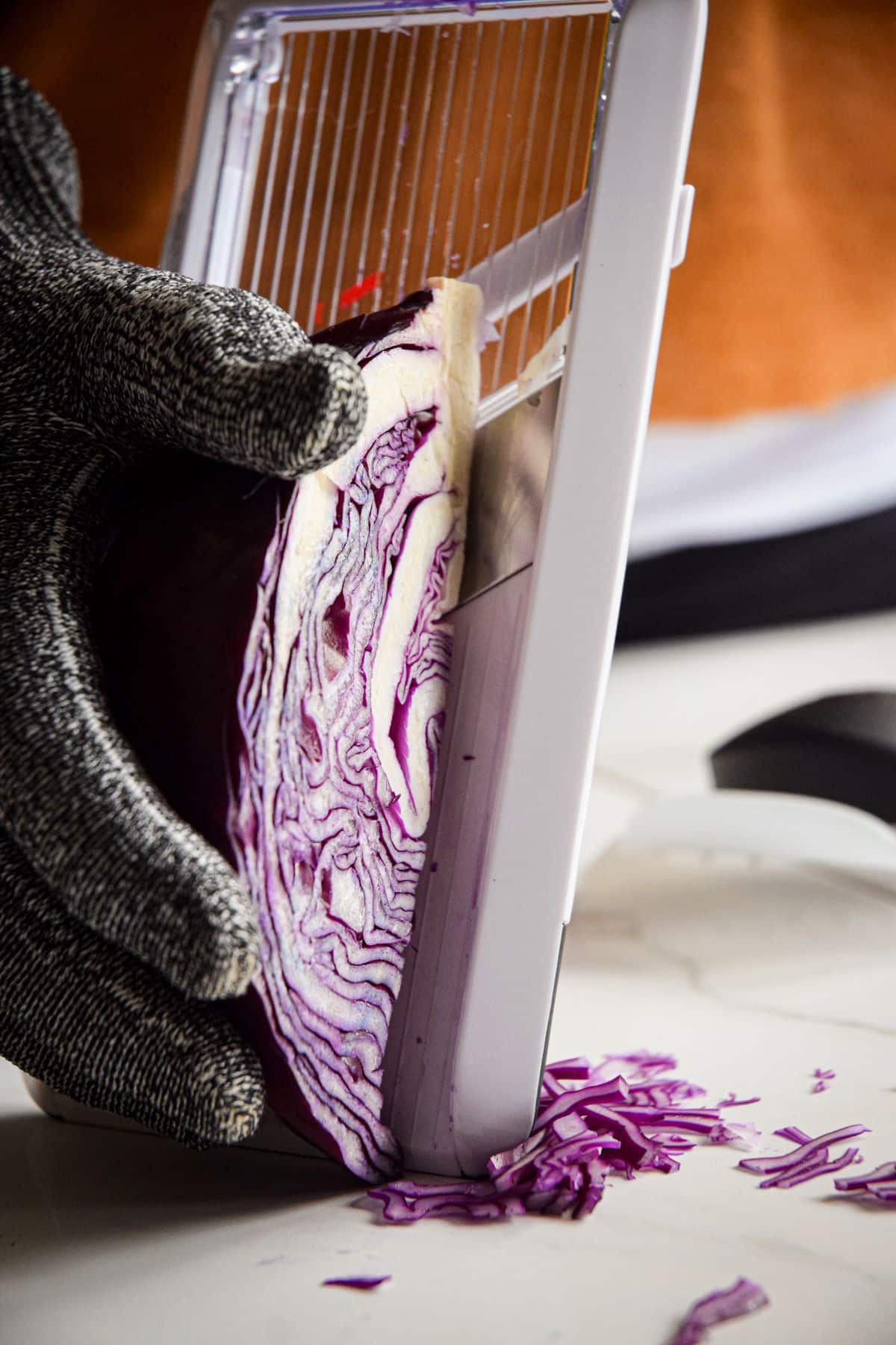 Red cabbage in hand with cut-resistant glove against mandolin.