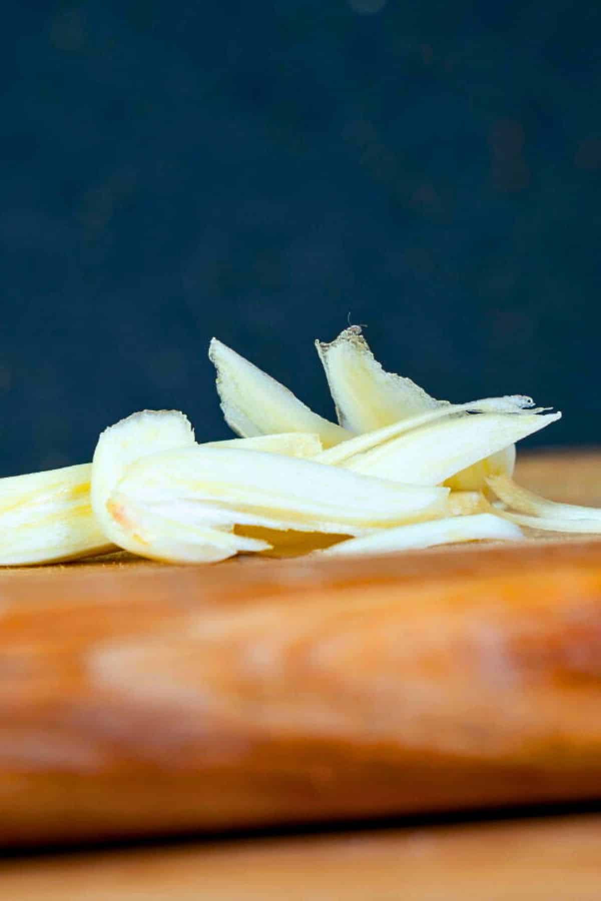 Sliced garlic on cutting board.