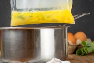 Raw scrambled egg in zip top bag over pot.