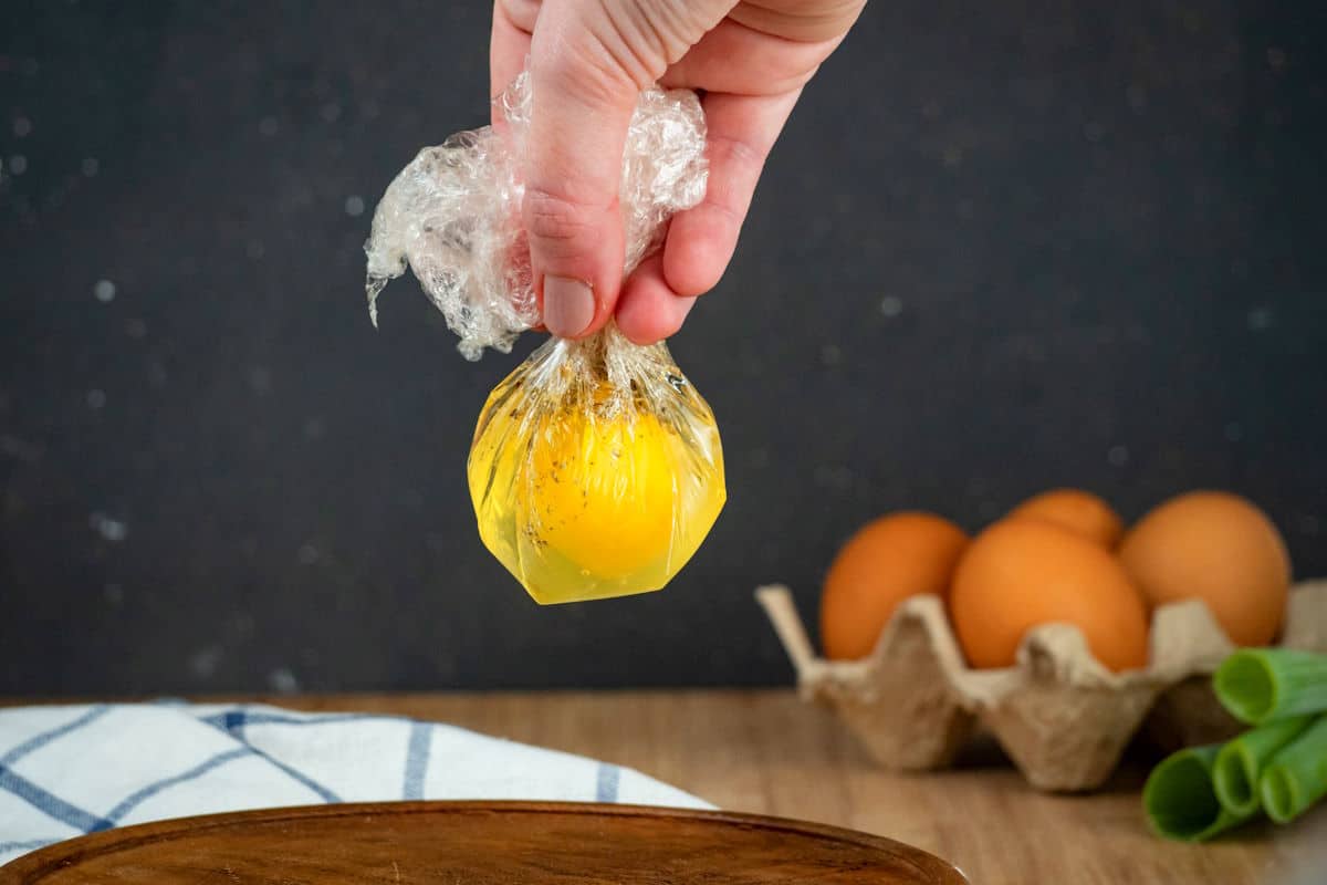 Egg in plastic wrap pouch held in hand.