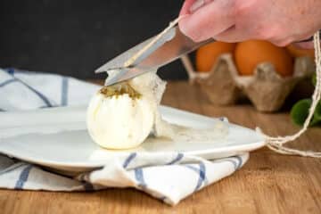 Soft boiled egg in plastic wrap pouch and scissors cutting the twine.