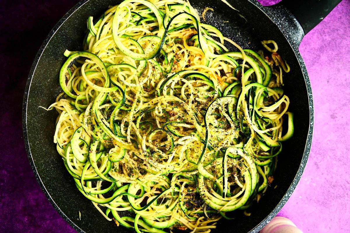 Zucchini noodles in pan with seasoning.