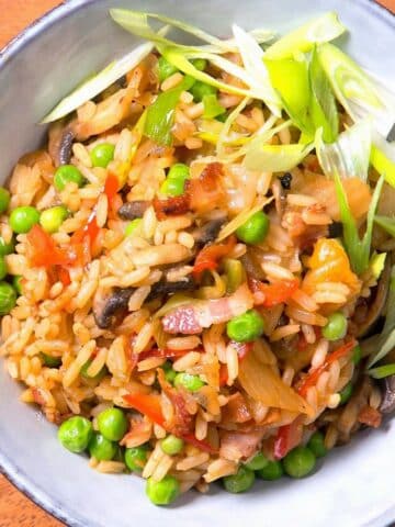 Kimchi bacon fried rice on a plate on brown background.