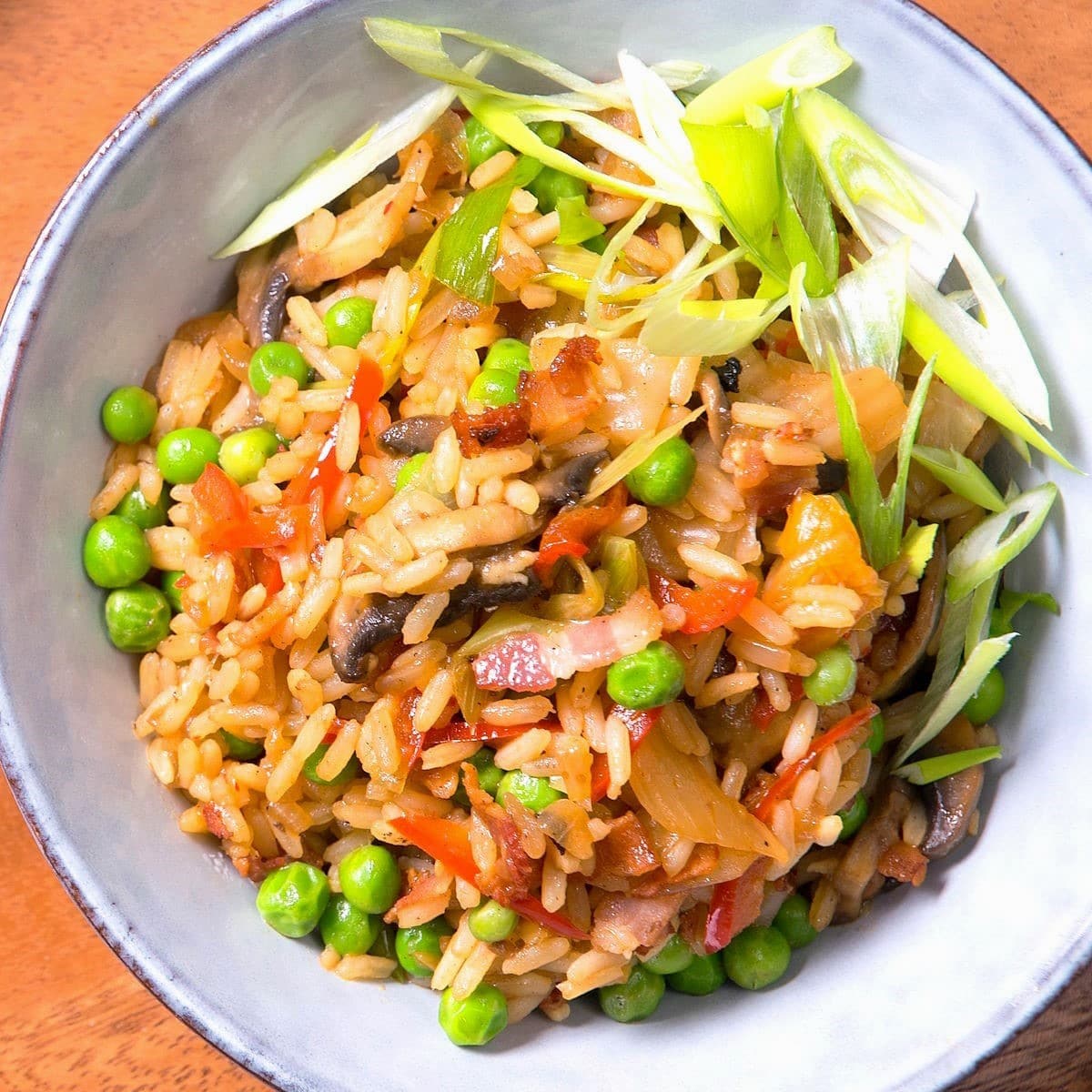 Kimchi bacon fried rice on a plate on brown background.