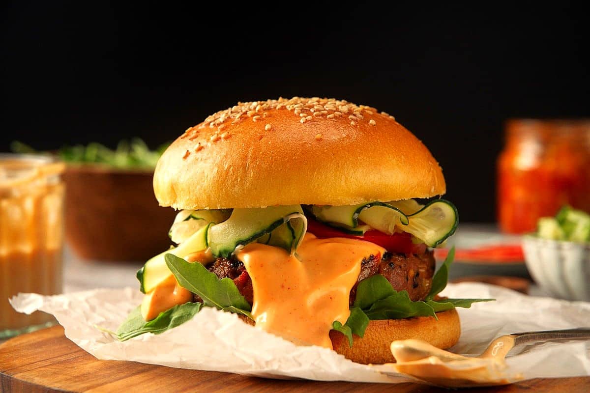 Kimchi burger with kimchi sauce on parchment.
