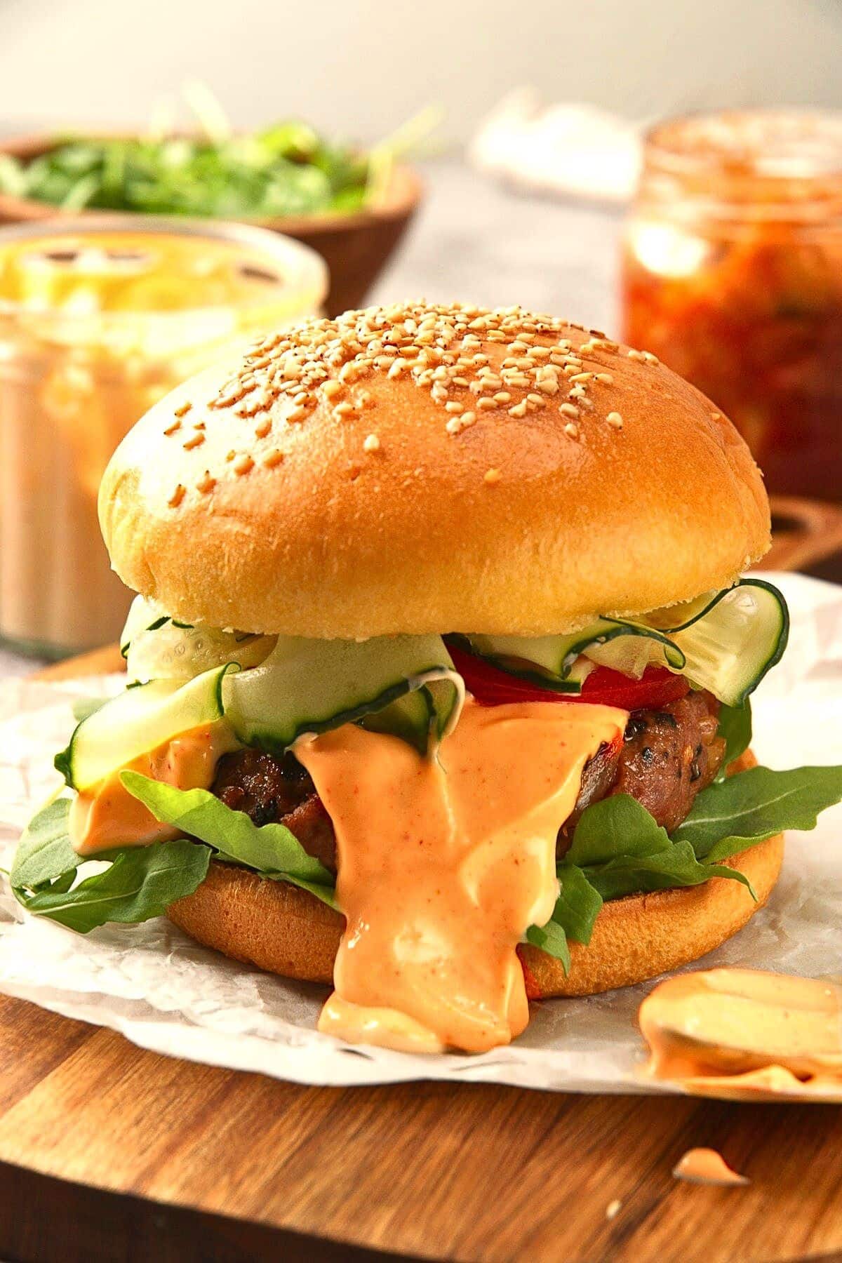 Kimchi burger with sesame seed bun on parchment.