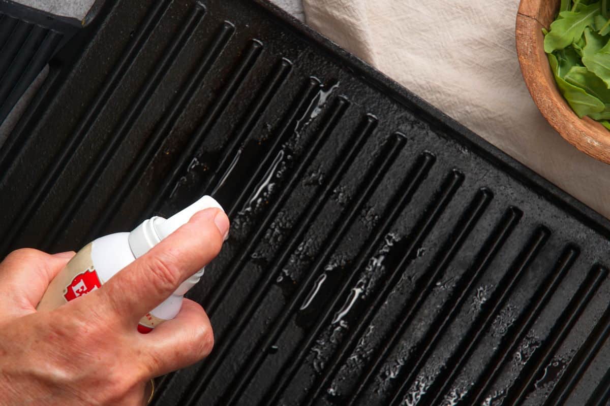 Grill pan getting sprayed with oil.