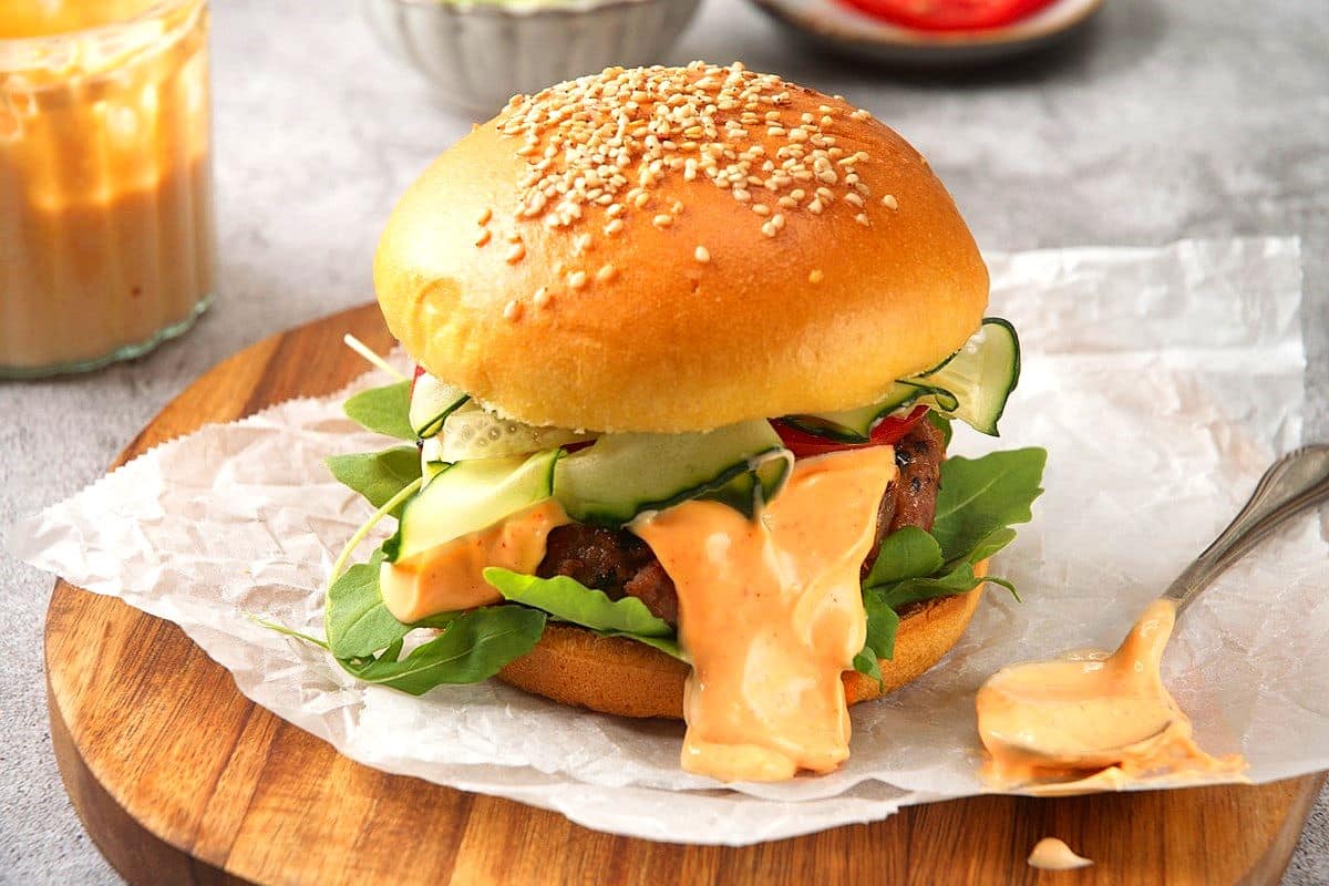 Kimchi beef burger with creamy kimchi sauce on serving board.