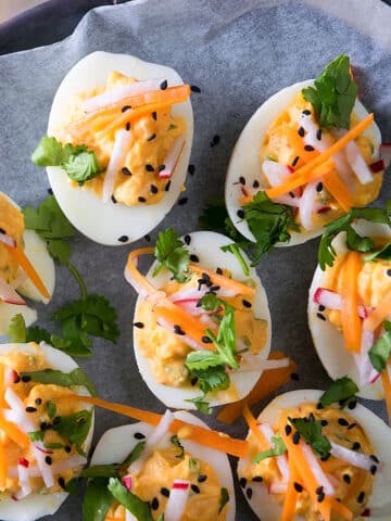 Deviled eggs with kimchi, pickled veggies and cilantro on parchment.