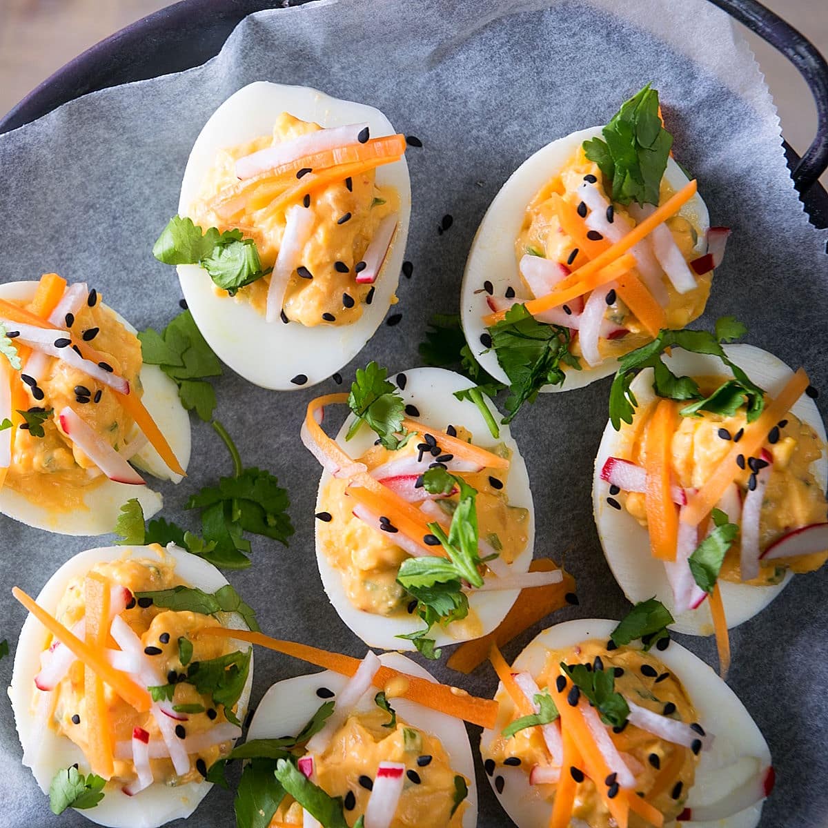 Deviled eggs with kimchi, pickled veggies and cilantro on parchment.