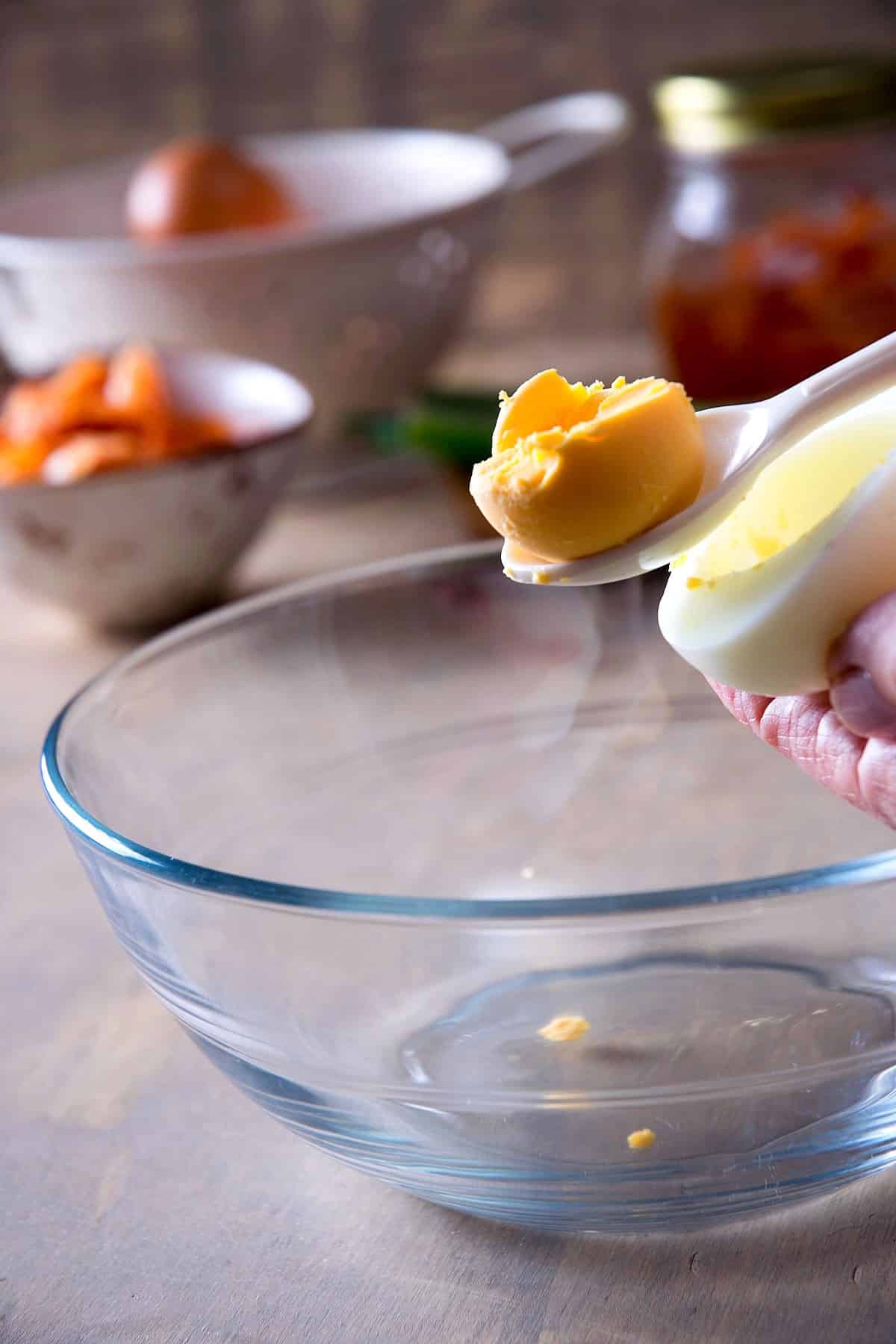 Cooked egg yolk in a spoon over bowl.