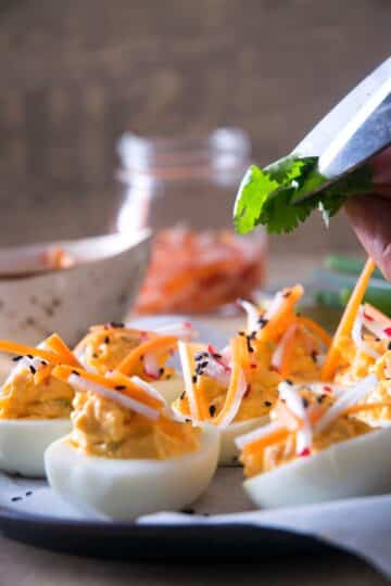 Deviled eggs and scissors cutting cilantro.