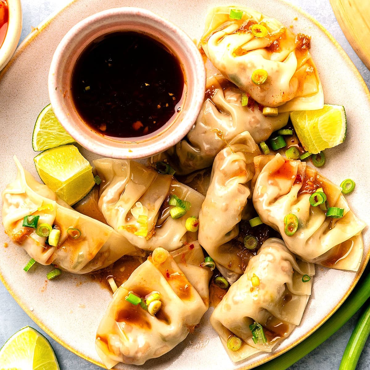 Kimchi dumplings arranged on plate with dipping sauce.