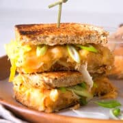 Kimchi grilled cheese sandwiches stacked on serving tray with skewer.