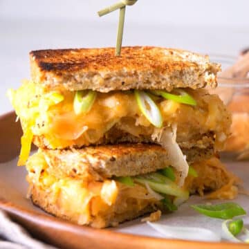 Kimchi grilled cheese sandwiches stacked on serving tray with skewer.