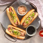 Kimchi hot dogs with small bowls of toppings on serving tray.